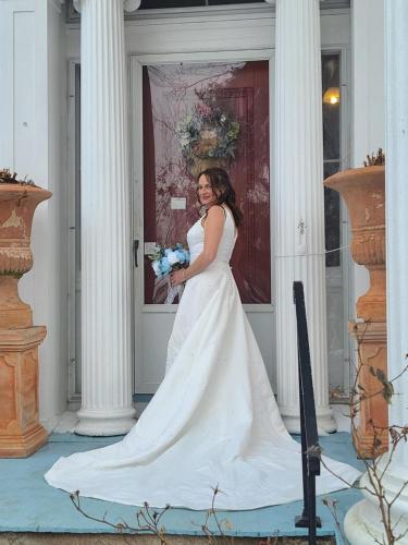 a woman in a white wedding dress holding a bouquet at House of 1833 Bed and Breakfast in Mystic