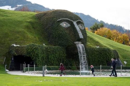 a statue of a head with people walking by a fountain at Ferienwohnung am Waldweg in Kolsass