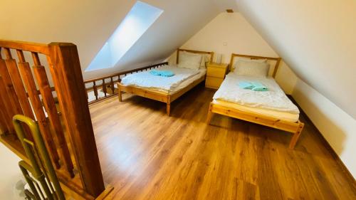 a attic room with two beds and wooden floors at Hotel Pod Kokšínem in Spálené Poříčí