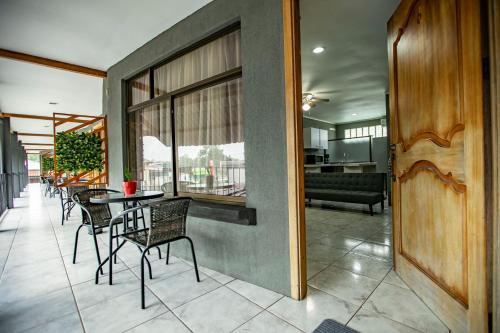Coati Arenal Lodge في فورتونا: غرفة طعام مع كراسي وطاولة ونوافذ