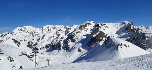 a snow covered mountain with people on a ski lift at Studio aux pieds des pistes Roche Béranger in Chamrousse