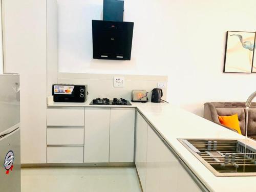 a white kitchen with a stove and a microwave at Luxury Comfortable One Bedroom In Lekki Phase1 in Lekki