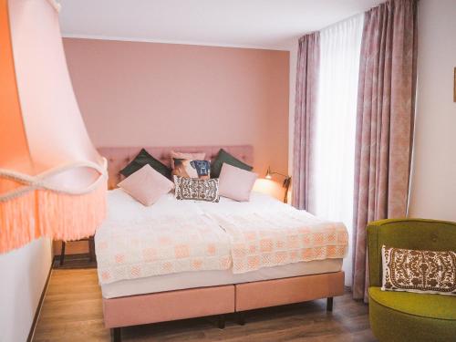 Un dormitorio con una cama con almohadas. en Tante ALMA's Mülheimer Hotel en Mülheim an der Ruhr