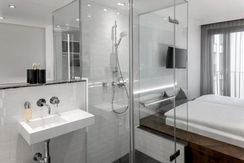 a white bathroom with a sink and a shower at Hotel AMANO Grand Central in Berlin