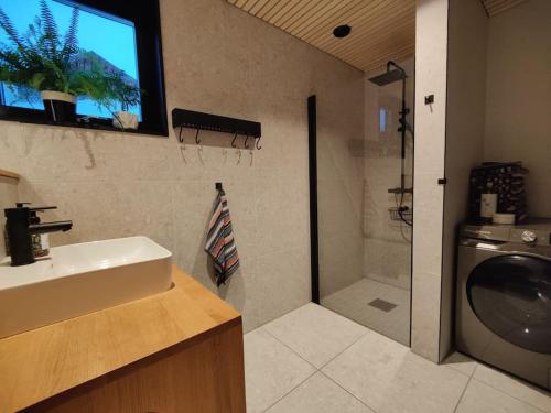 een badkamer met een wastafel en een douche en een televisie bij Huset ved skogen in Isfjorden