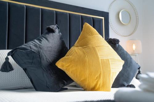 duas almofadas pretas e amarelas numa cama em Brulee House - Luxury 2 Bed Apartment in Aberdeen Centre em Aberdeen