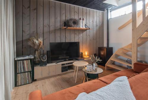 een woonkamer met een televisie en houten wanden bij La Casa Gardenia in Drunen