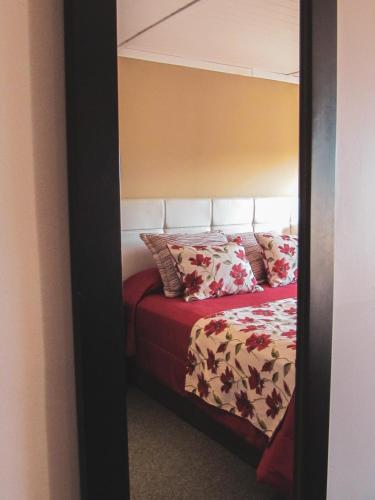 a bedroom with a bed with a red blanket and pillows at Boutique Hotel La Cantera in El Calafate