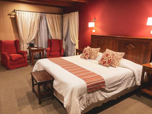 een slaapkamer met een groot bed en 2 rode stoelen bij Boutique Hotel La Cantera in El Calafate