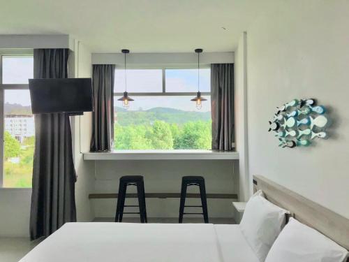 a room with a bed and a window and chairs at Slowlife Beach in Nai Yang Beach