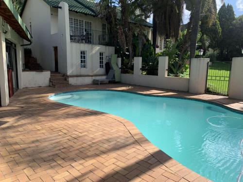 a swimming pool in front of a house at Safari Apartments -Beautiful 3 bedrooms, 10-seater dining , TV room, Garden & Pool in Johannesburg