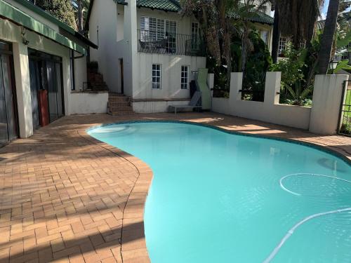 a large blue swimming pool in front of a house at Safari Apartments -Beautiful 3 bedrooms, 10-seater dining , TV room, Garden & Pool in Johannesburg