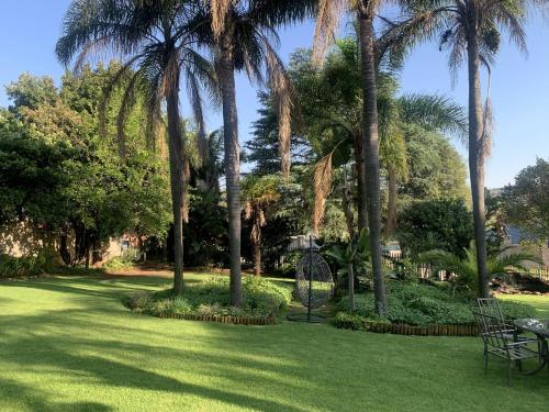 a park with palm trees and a bench in the grass at Safari Apartments -Beautiful 3 bedrooms, 10-seater dining , TV room, Garden & Pool in Johannesburg