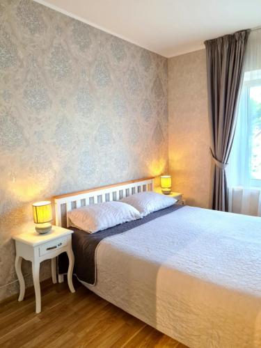 a bedroom with a bed and two lamps on a table at Old Town Apartment in Telšiai