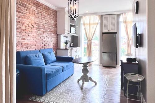 胡志明市的住宿－HOME by FLATTO APARTMENT，客厅设有蓝色的沙发和砖墙
