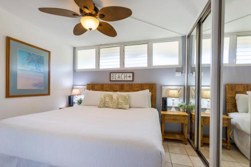 een slaapkamer met een wit bed en een plafondventilator bij Hale Ono Loa 102 in Kahana
