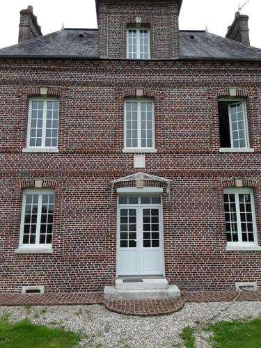 un edificio de ladrillo con una puerta blanca. en Chez DOUDOU entre terre et mer, en Bretteville-Saint-Laurent