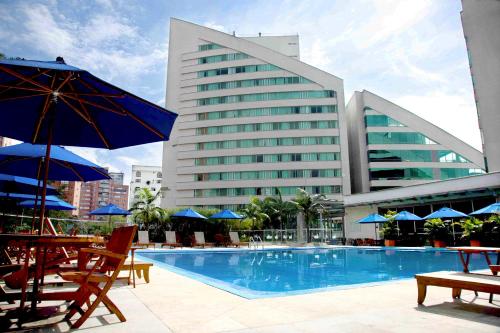una piscina con sillas y sombrillas junto a un hotel en Hotel San Fernando Plaza, en Medellín