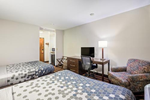 Cette chambre comprend deux lits, un bureau et une chaise. dans l'établissement Econo Lodge Milwaukee Airport, à Milwaukee