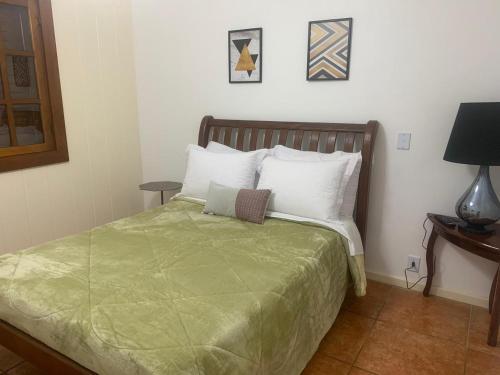 a bedroom with a bed with a green blanket at Casa Riacho Verde in Petrópolis