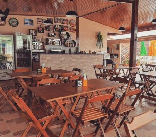 an empty restaurant with wooden tables and chairs at Recanto Primavera Ubatuba in Ubatuba