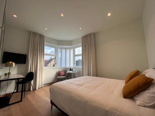 a bedroom with a bed and a desk and a window at Tuss in Kortrijk