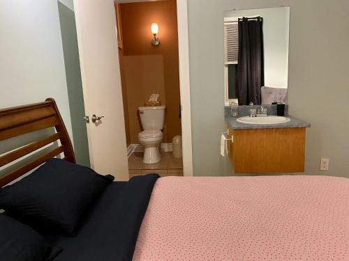 ein Schlafzimmer mit einem Bett und ein Badezimmer mit einem Waschbecken in der Unterkunft Auberge du Monde in Trois-Rivières