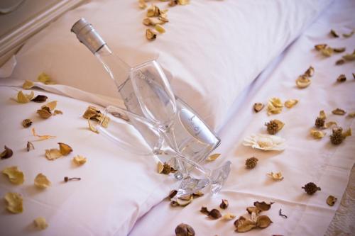 a glass bottle on a bed with flowers on it at Casale D' Or in Palermo