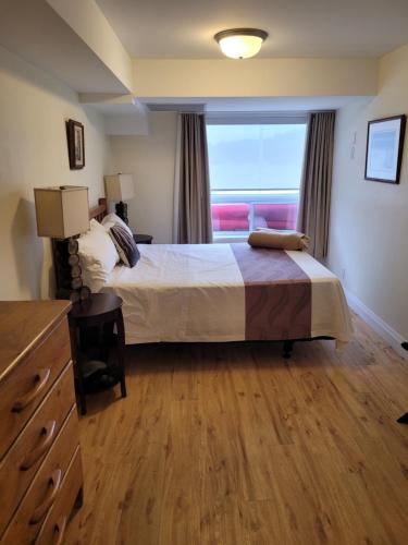 Muskoka Lakes Hotel and Resorts في ميناء كارلينج: غرفة نوم بسرير كبير ونافذة