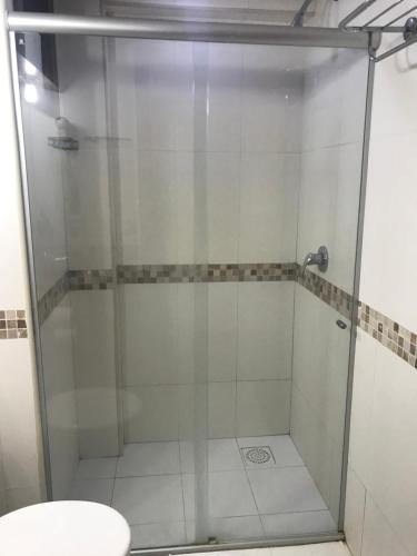 La salle de bains est pourvue d'une douche en verre et de toilettes. dans l'établissement Kariri Beach - Apartamento Superior, à Cumbuco