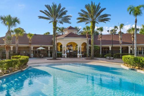 a swimming pool in front of a building with palm trees at Windsor Hills Resort- 204A in Orlando