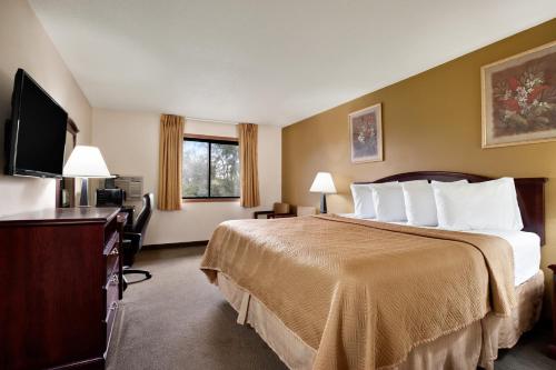a hotel room with a bed and a flat screen tv at Travelodge by Wyndham La Porte/Michigan City Area in LaPorte