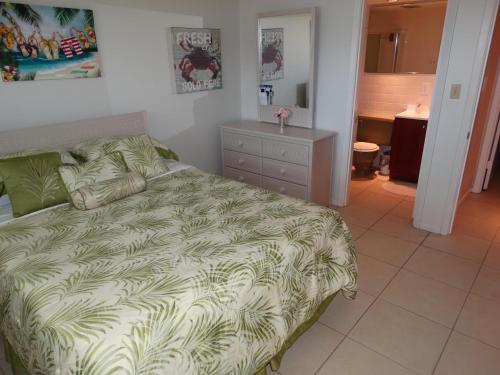 een slaapkamer met een bed met een groen dekbed bij Spanish Main Unit 4- Direct Oceanfront Condo! in Cocoa Beach