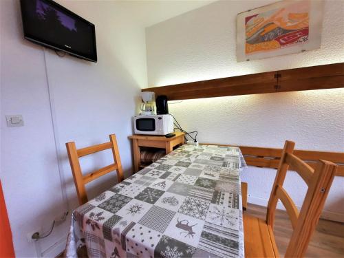 une salle à manger avec une table et un four micro-ondes dans l'établissement Studio 2 pers - Ski aux pieds, balcon, centre Menuires - FR-1-452-216, aux Menuires
