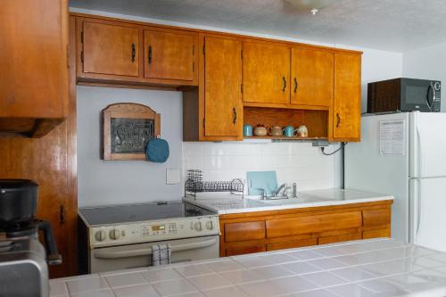 a kitchen with wooden cabinets and a white refrigerator at Cozy 1 Bedroom Unit - 4 Blocks from Jax Beach Pier! in Jacksonville Beach