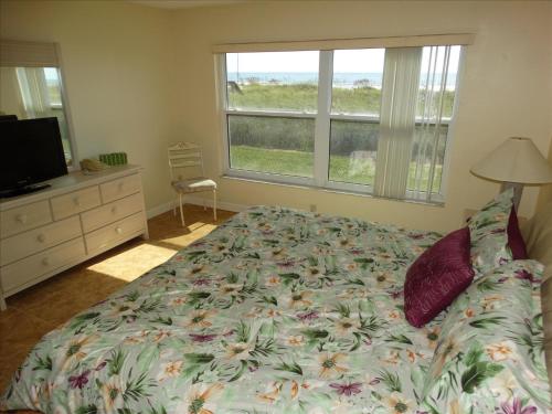 una camera con letto, televisore e finestra di Spanish Main Unit 1- Direct Oceanfront Condo! a Cocoa Beach