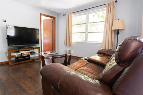 a living room with a leather couch and a television at Cozy 1 Bedroom Unit - 4 Blocks from Jax Beach Pier! in Jacksonville Beach