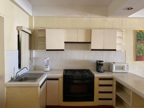 a kitchen with a stove and a microwave at Departamento 1 RECAMARA - Frente al Mar Marina del Rey in Mazatlán