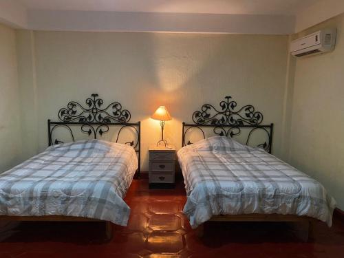 een slaapkamer met 2 bedden en een lamp erin bij Departamento 1 RECAMARA - Frente al Mar Marina del Rey in Mazatlán