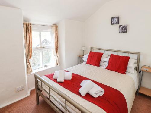 1 dormitorio con 1 cama grande con almohadas rojas y blancas en Jasmine Cottage, en Windermere