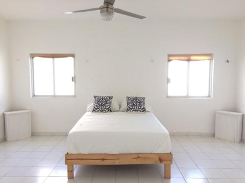 un letto in una camera bianca con due finestre di Apartment with fast WIFI near Cancun downtown a Cancún
