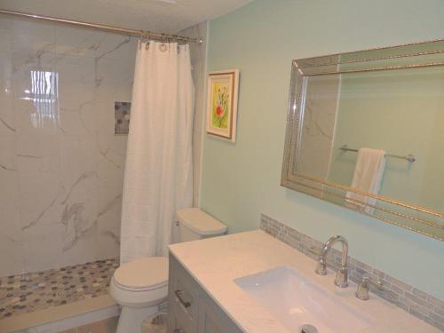 een badkamer met een wastafel, een toilet en een spiegel bij Renovated, Ocean Beach Villas Unit 201- Direct Oceanfront Condo! in Cocoa Beach