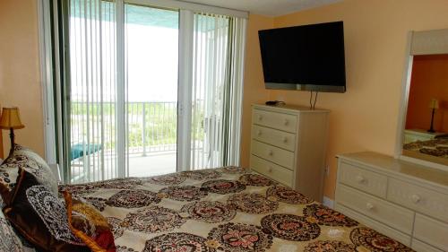 a bedroom with a bed with a dresser and a television at Ocean Beach Villas Unit 203- Direct Oceanfront Condo! in Cocoa Beach