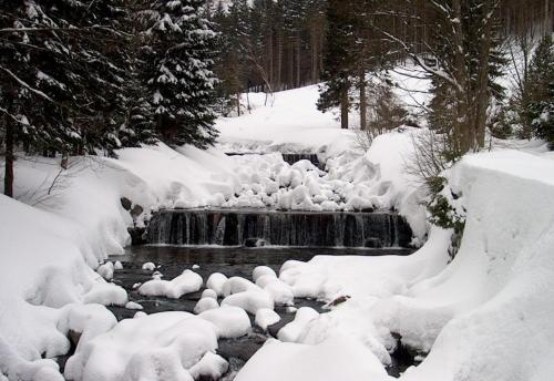 a stream covered in snow next to a waterfall at VILLA ANNA in Cerny Dul