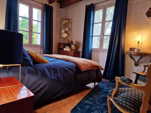 een slaapkamer met blauwe gordijnen en een bed en een stoel bij Maison Cassin47 in Lavergne