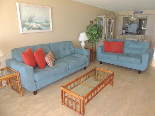 a living room with a blue couch and two tables at Ocean Beach Villas Unit 302- Direct Oceanfront Condo! in Cocoa Beach