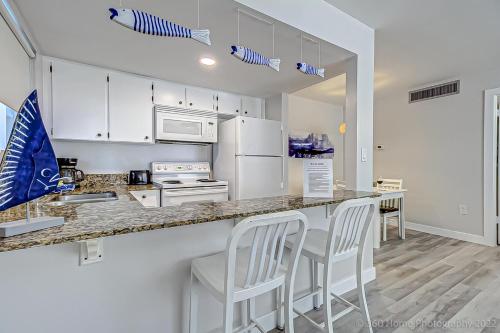a kitchen with white cabinets and a counter with stools at Twins Inn & Apartments in St Pete Beach