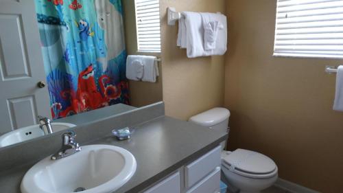 a bathroom with a sink and a toilet and a shower curtain at Windsor Hills Resort- 401 in Orlando