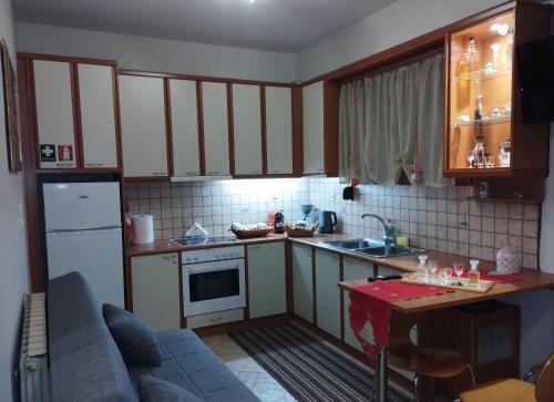 une petite cuisine avec des placards blancs et une table dans l'établissement Casa D' Irene, à Karpenísi