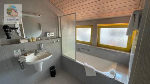 ein Bad mit einem Waschbecken und einem Spiegel in der Unterkunft KRYSTALL Hotel in Filderstadt